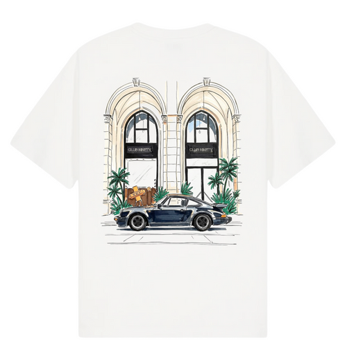 A white short-sleeve t-shirt featuring a colorful graphic print of a vintage blue sports car parked in front of a building with arched windows and palm trees. The image includes text overlays reading 'THE GALLERY DROP LA DOLCE VITA TEE' on the top left, 'CLUB NINETY' on the top right, and 'COLLECTIONS SS26 BEST SELLER' on the bottom.